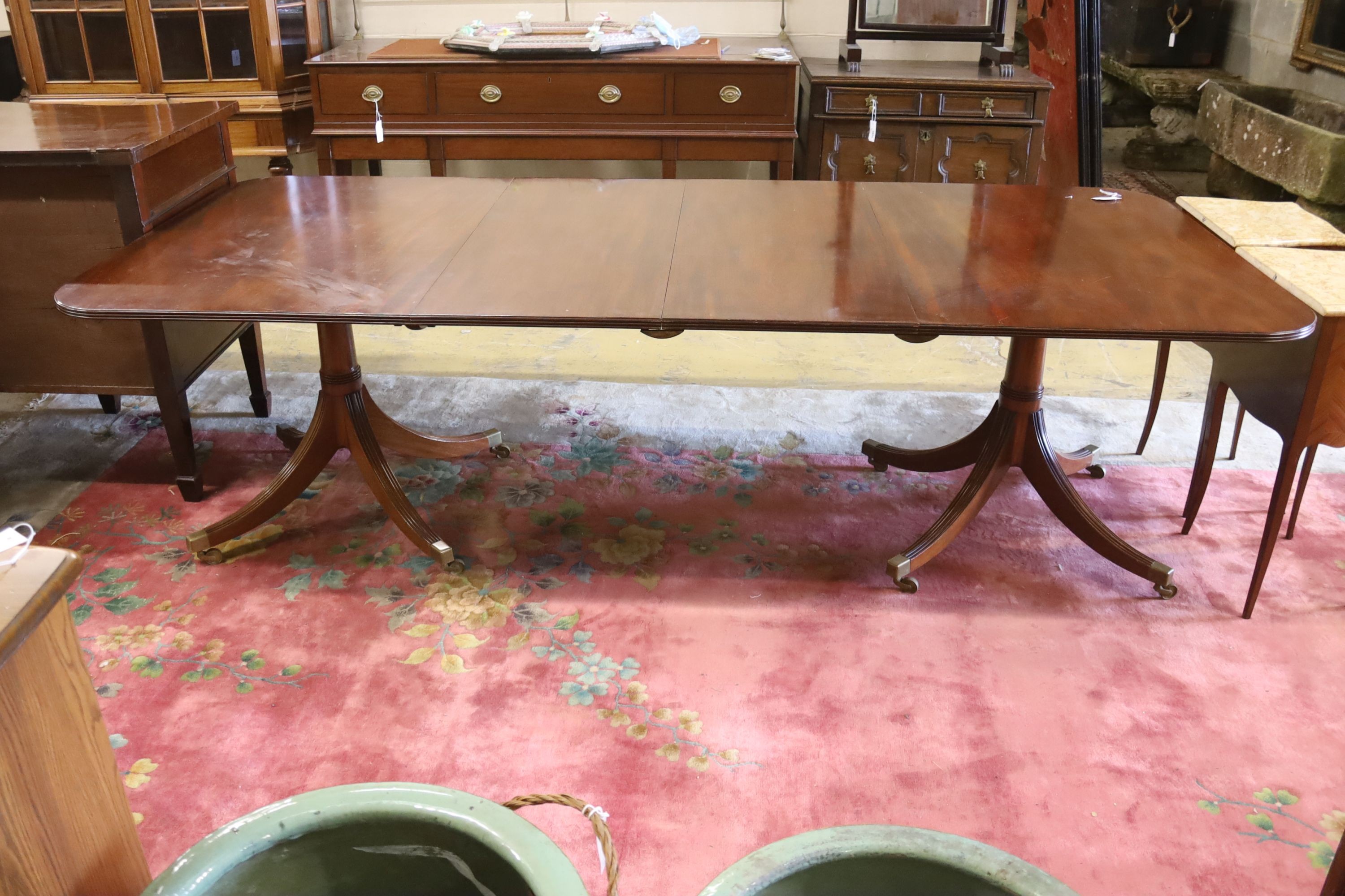A reproduction George III style mahogany twin pillar extending dining table, two spare leaves, length 244cm extended, width 107cm, height 72cm
